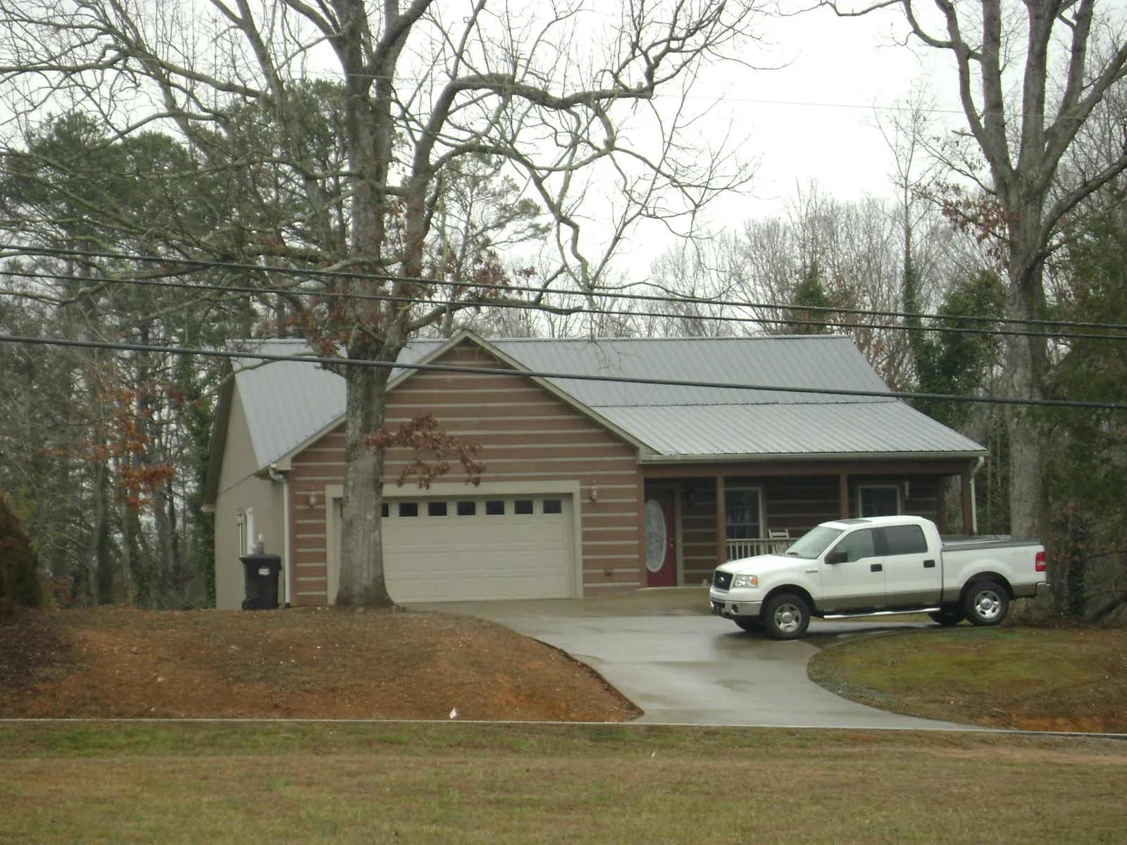 Gray metal roof on a log sided house with an attached two car garage in Cromwell